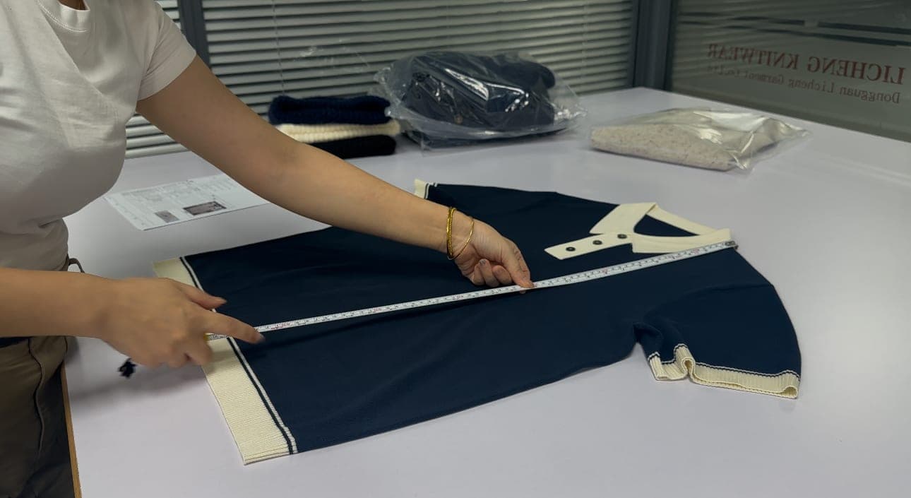 Measuring a finished knit polo against the spec sheet during quality control at Licheng Knitwear