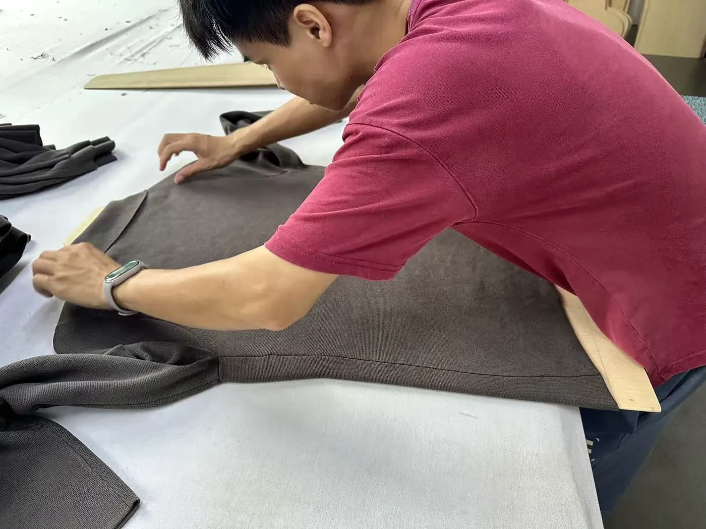 Steam pressing a knit garment during finishing at Licheng Knitwear