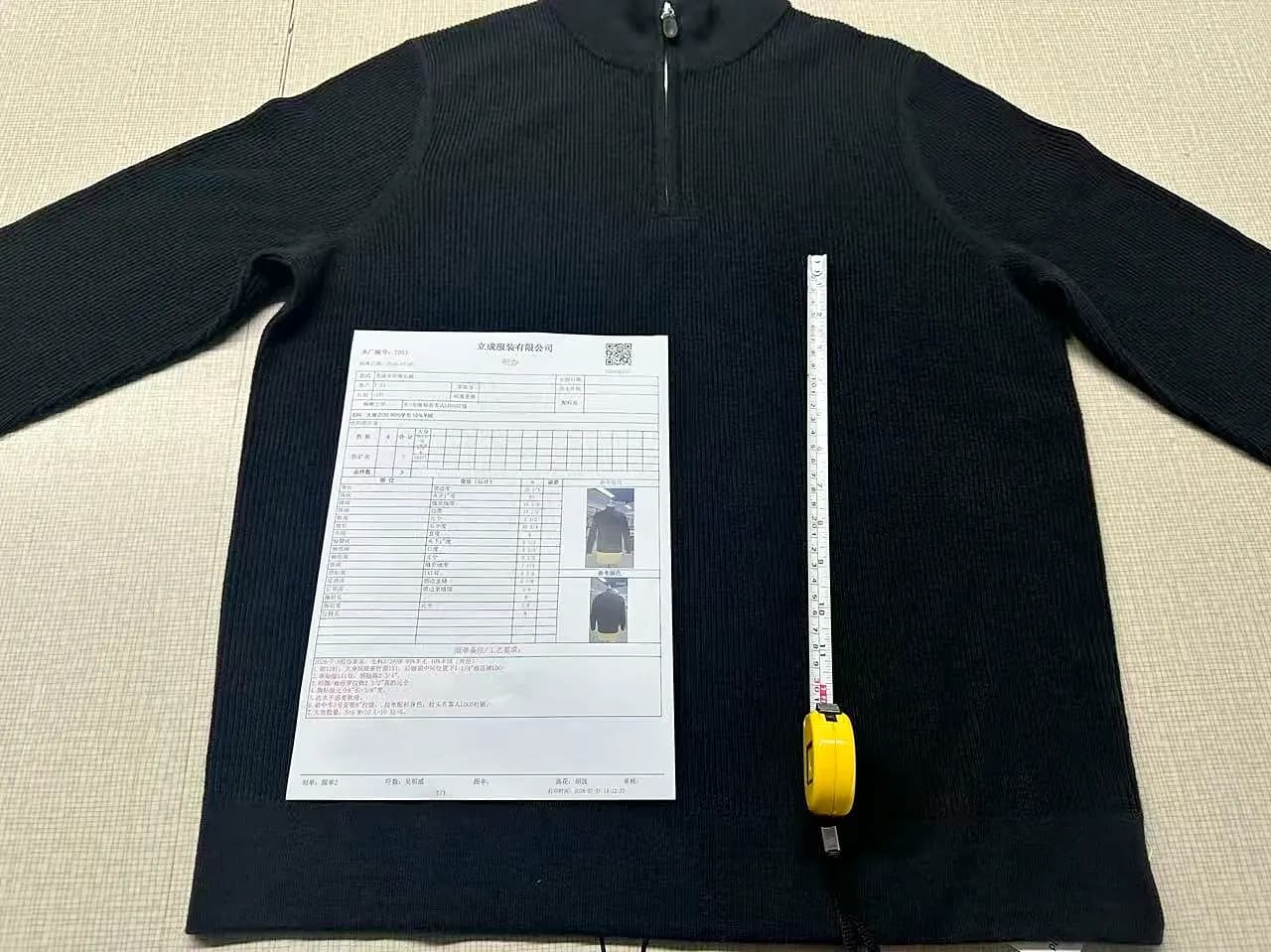 Knit pullover laid flat with its spec sheet and a tape measure