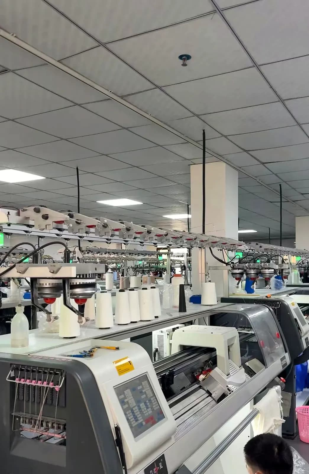 Rows of flat knitting machines running on the production floor