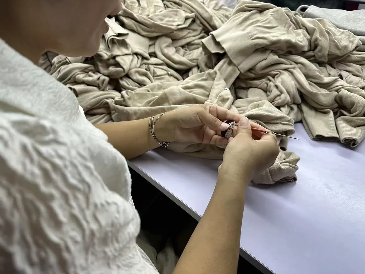Hands inspecting knitwear seams and finishing