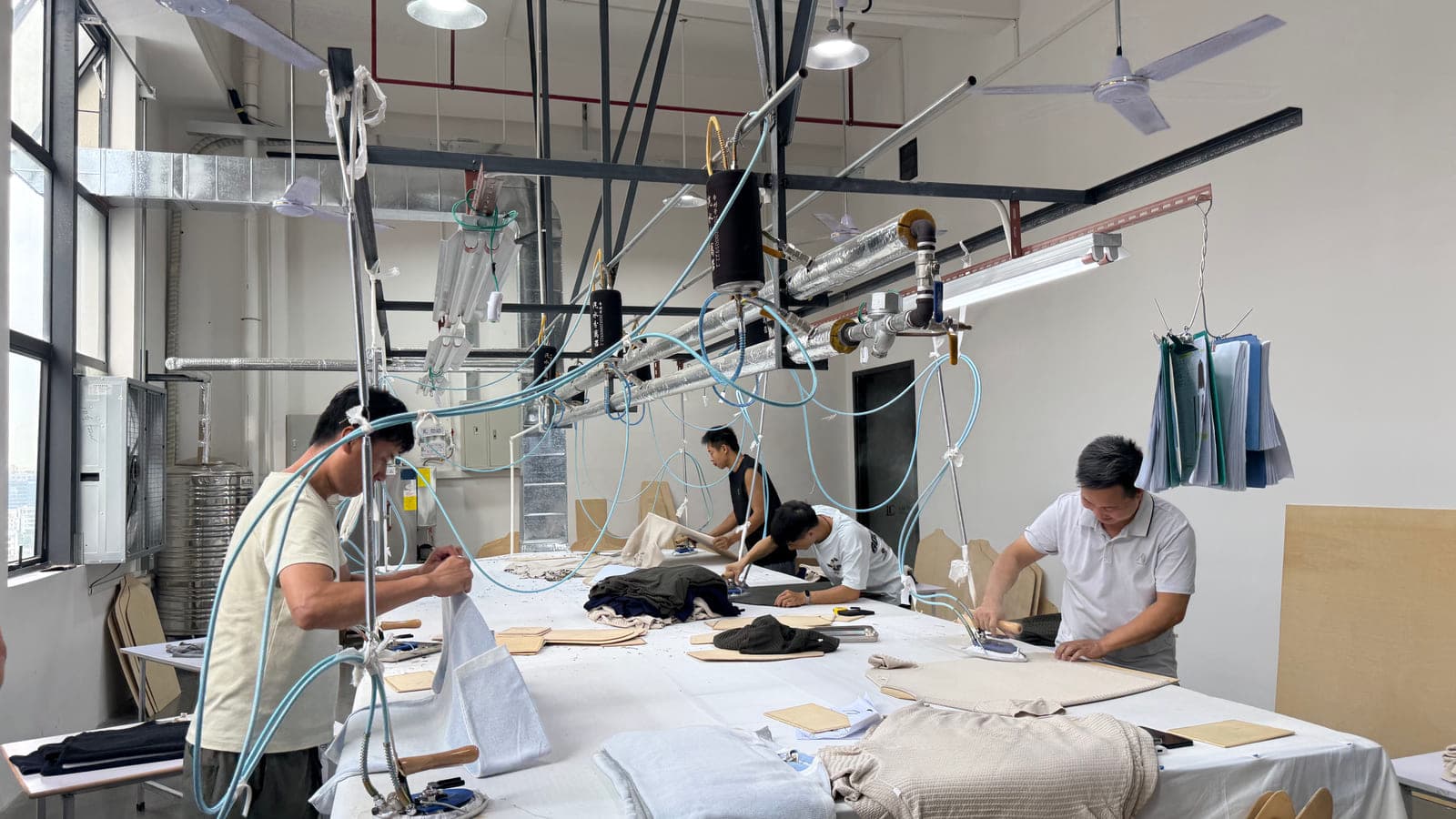 Pressing knitted sample pieces to shape on wooden boards in our Dongguan sampling room - where a buyer's reference photo becomes a first sample