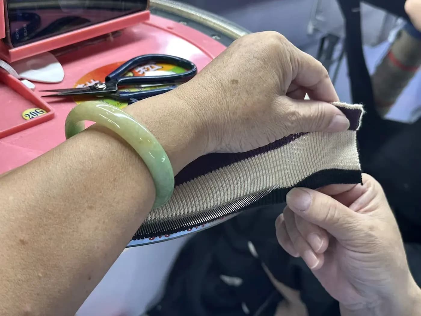 Technician joining knitwear panels by hand at a linking machine
