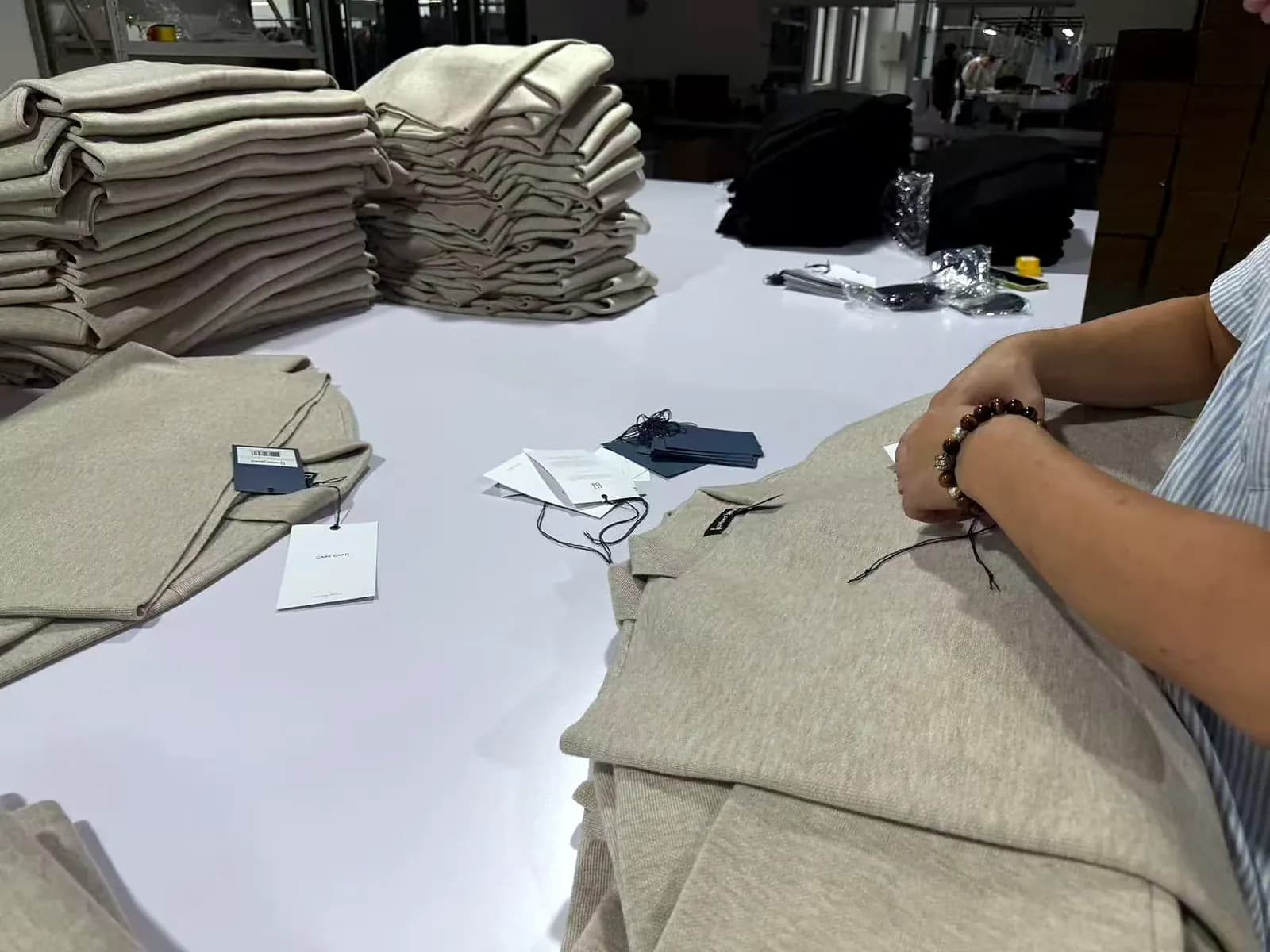 Hangtags and private-label trims being attached to folded knitwear before packing.