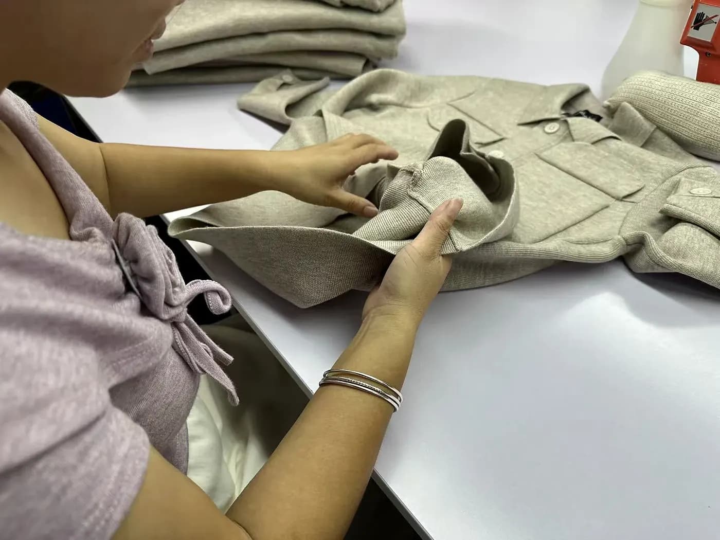 Hands inspecting knitwear seams and finishing