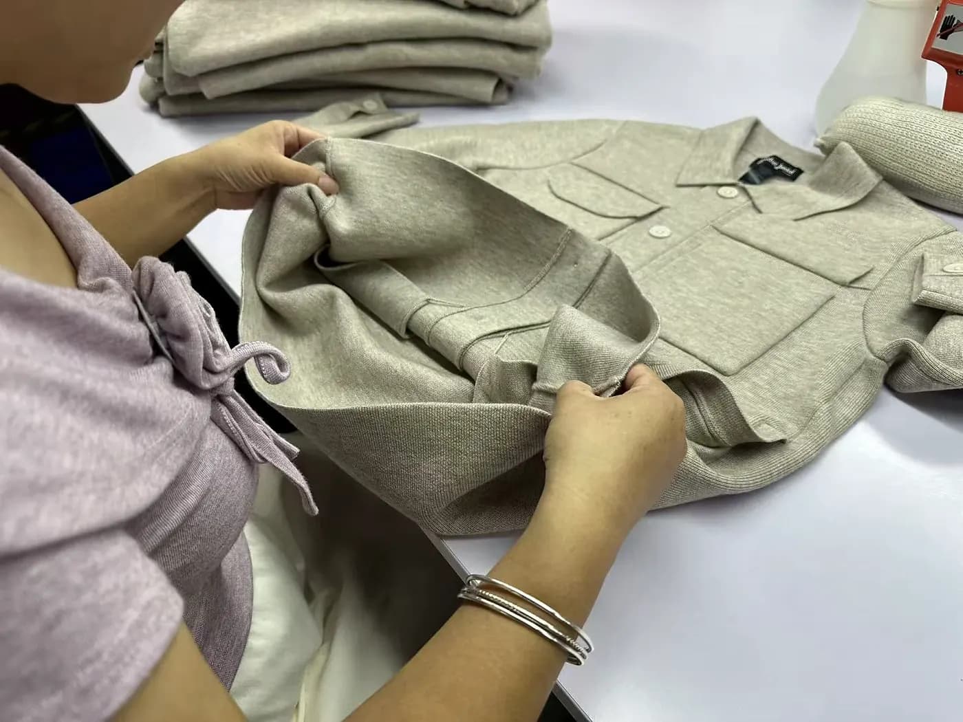 Hands checking knitwear seam finish before packing.