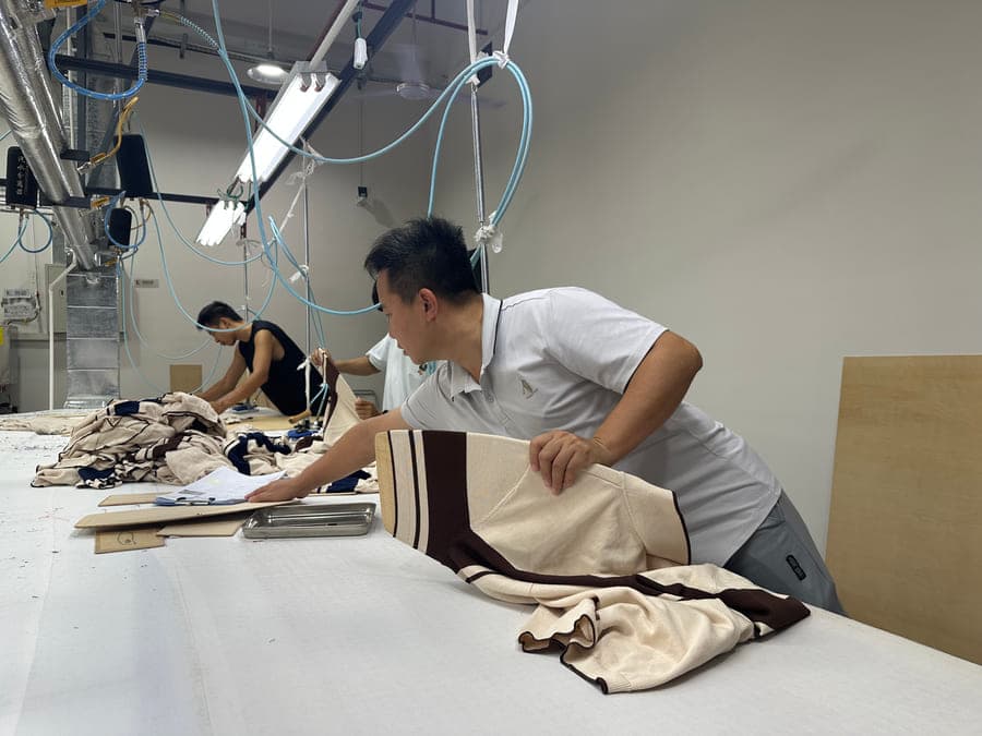 Sample display — worker presenting a finished striped sweater