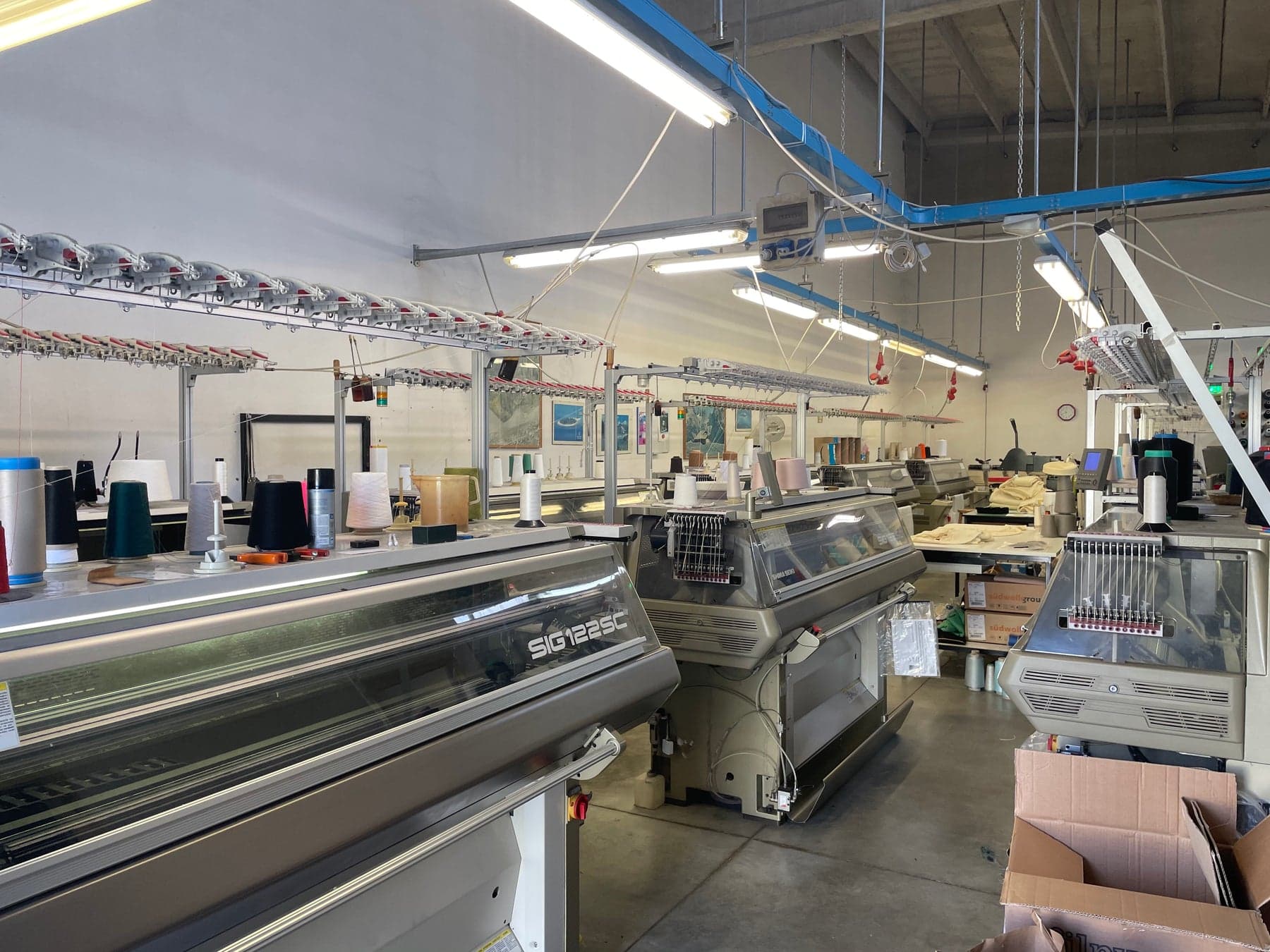 Rows of computerized flat-knitting machines on the production floor
