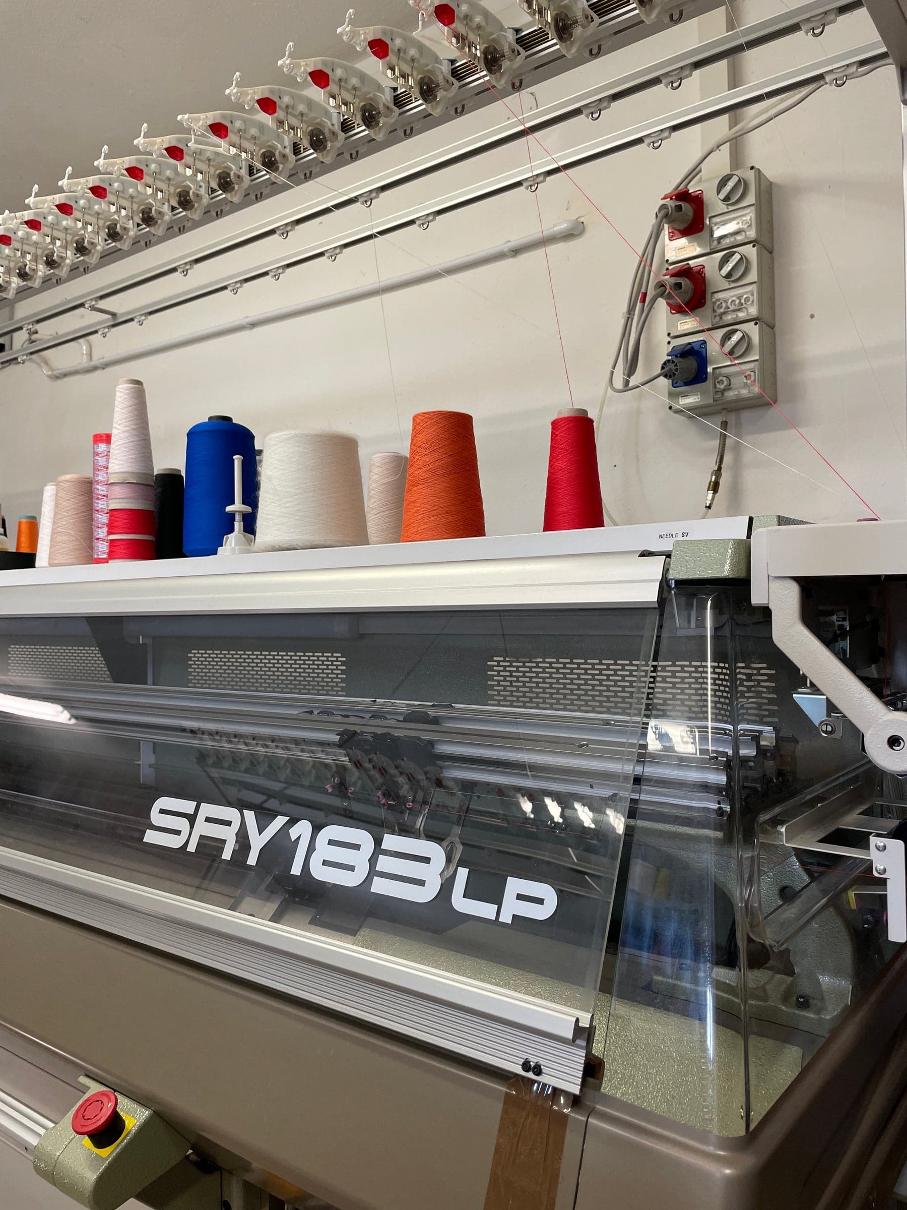 Flat-knitting machine with colored yarn cones ready for production